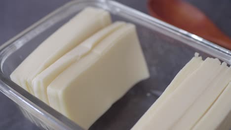 close up of sliced cheese in a glass container