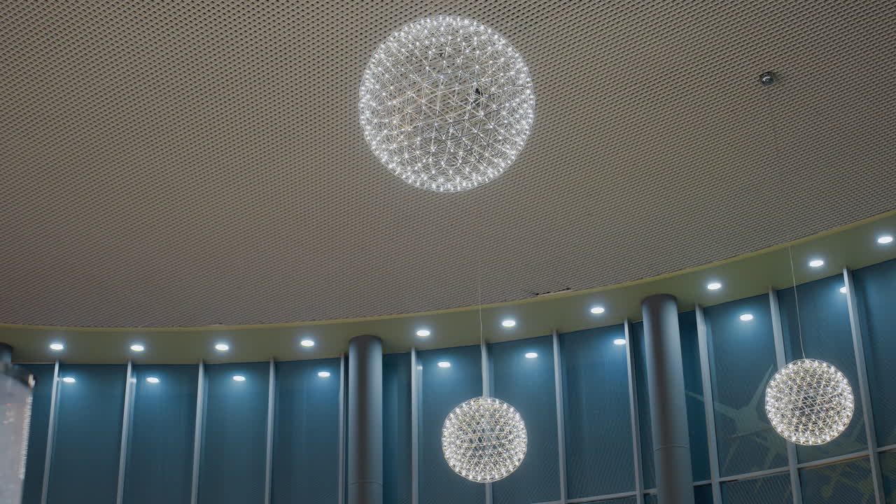 Smiling young woman taking a selfie in front of a beautifully decorated Christmas tree with glowing lights and colorful ornaments, capturing a festive holiday moment