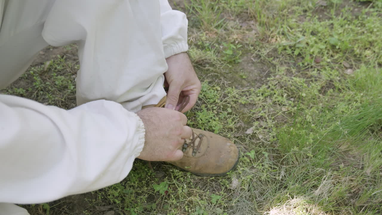 Person tying boots in protective beekeeping suit
