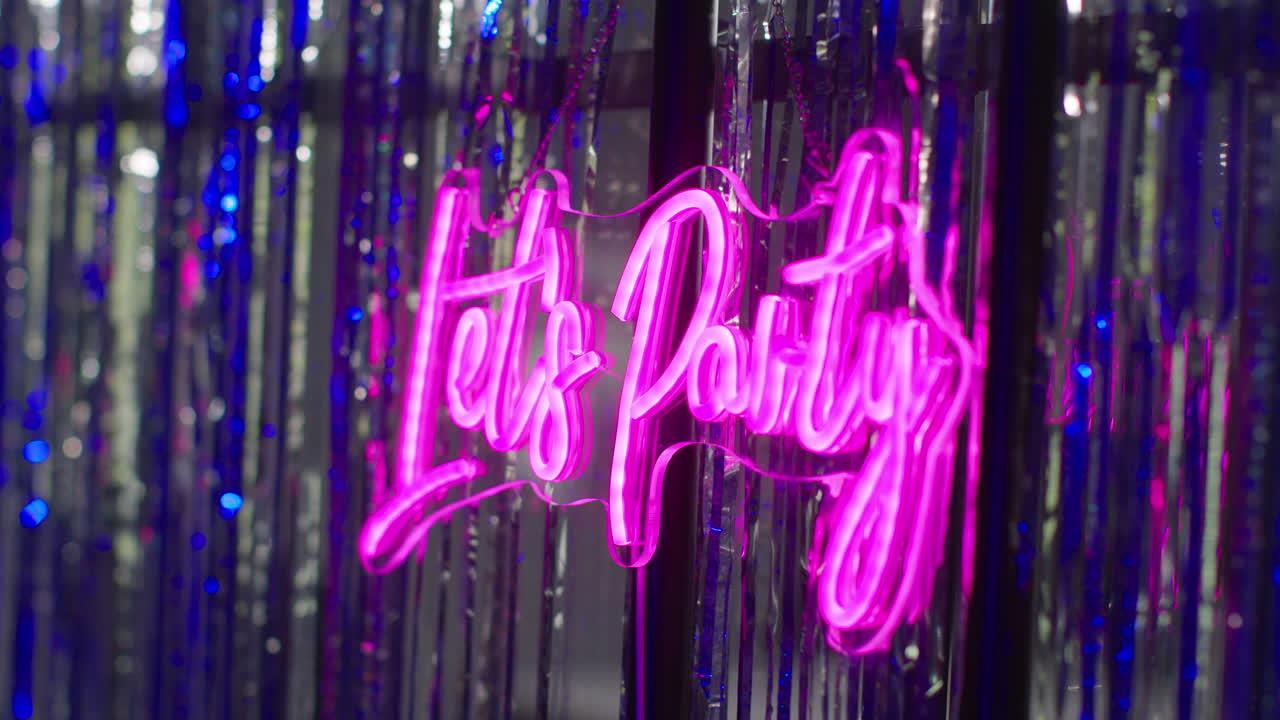 cerca de un letrero de neón "vamos a festejar" colgado contra el bronceado en un club nocturno o en una feria