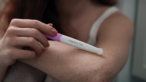 primer plano de una mujer caucásica en el baño esperando el resultado de una prueba de embarazo.