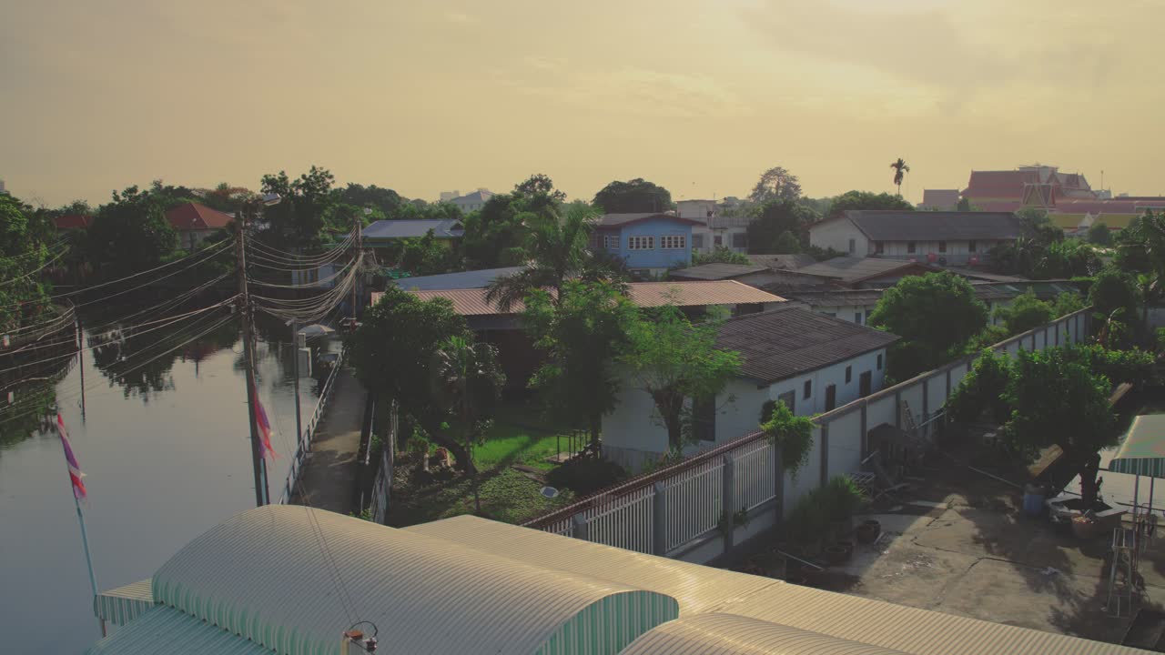 A peaceful canal neighborhood in Bangkok during golden hour with homes and lush greenery