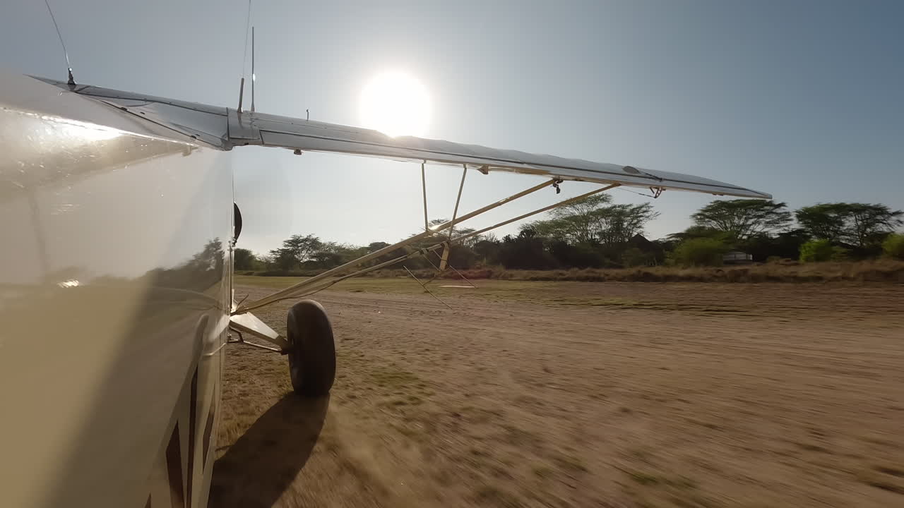 Piccolo aereo di profilo che rulla su una pista erbosa