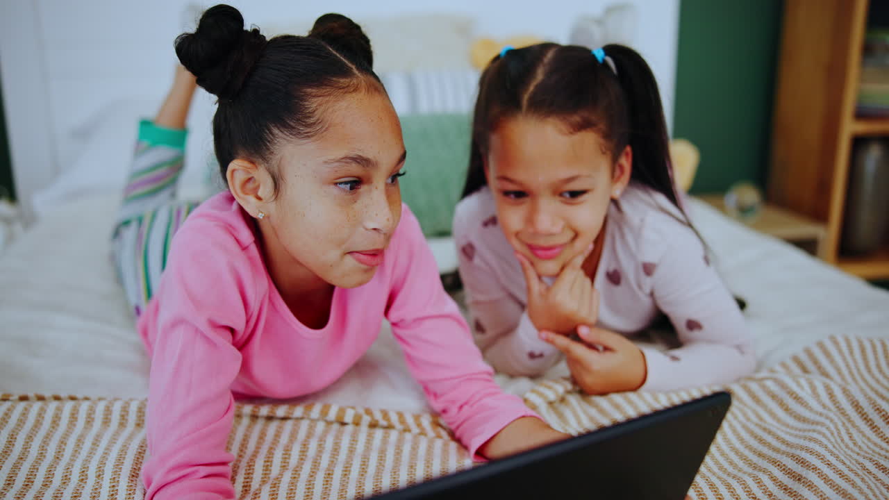 Two girls using a tablet in bedroom