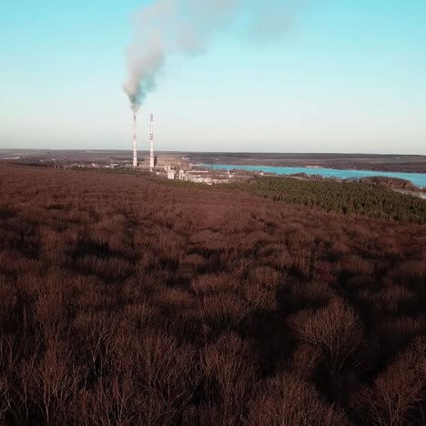 power plant is operating near the forest and the river in the autumn. aerial view