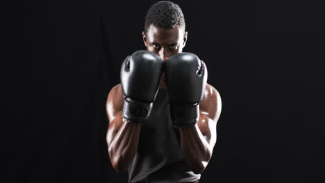 afrikanisch-amerikanischer boxer in einer defensiven haltung auf schwarzem hintergrund