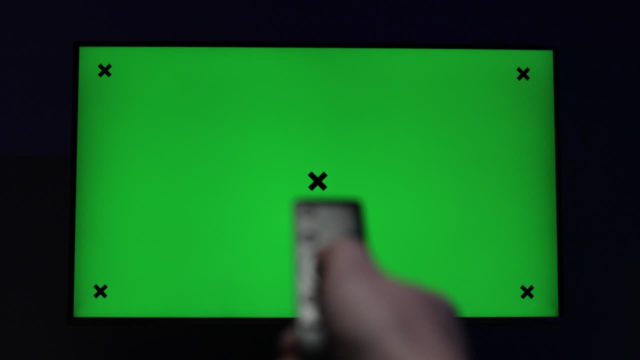 녹색 모형 화면 스마트 tv를보고 현대적인 검은 리모컨을 사용하여 크로마 키 tv와 리모컨 채널에 의해 채널을 변경하고 인터넷 tv 녹색 화면을 서핑하는 사람