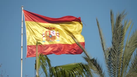 Cámara-Lenta-De-La-Bandera-Española-Ondeando-En-El-Viento-Y-La-Palmera