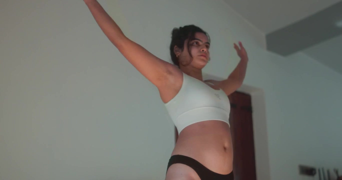 Giovane donna che fa esercizi di salto energici al chiuso con le braccia alzate e movimenti veloci. Una scena di stile di vita fitness attivo adatta per concetti di cardio, benessere e allenamento a casa
