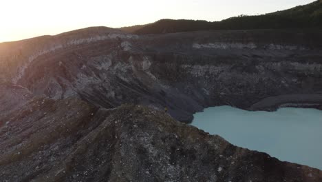 parallax drone shot of a person with yellow jacket walking on top of poas volcano in costa rica