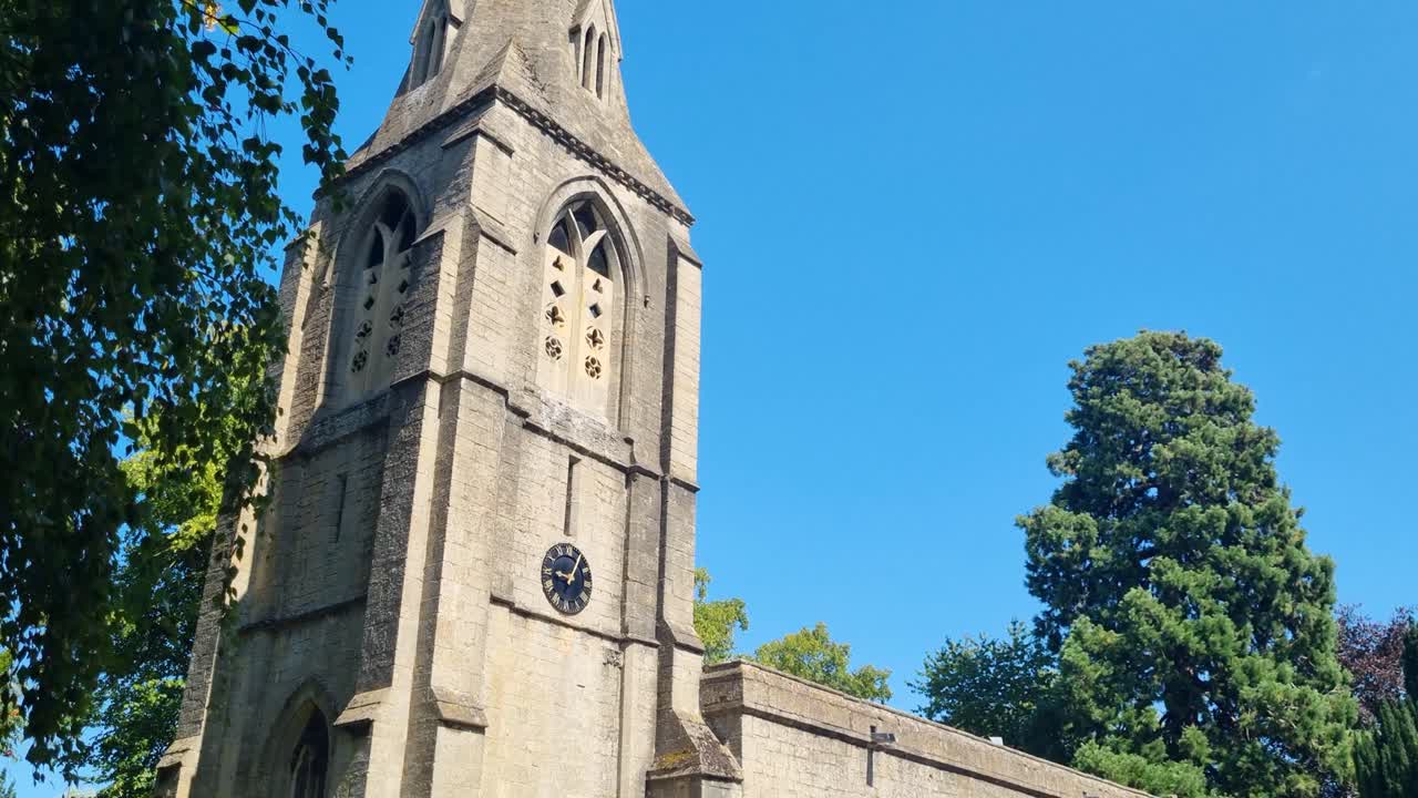 La storica chiesa di St Mary a Bainton, Cambridgeshire, Regno Unito, si erge sotto un cielo azzurro in un pomeriggio soleggiato, con il suo fascino senza tempo incorniciato da una vegetazione verdeggiante.