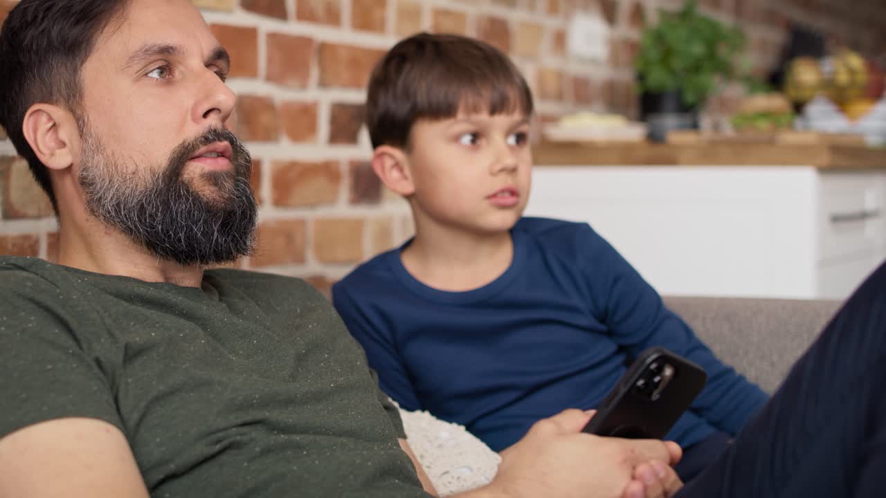 video de cerca de padre e hijo viendo televisión en casa