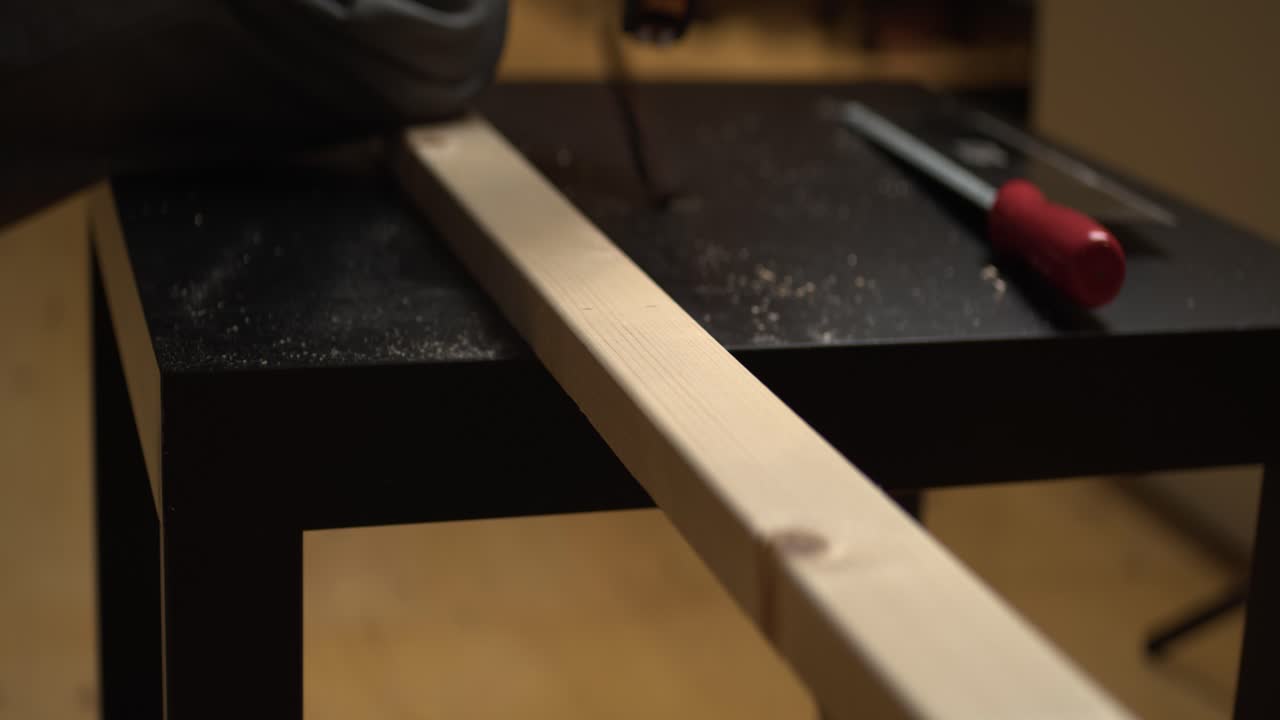 좁은 초점:남자는 작은 테이블에서 자르기 위해 소나무 재목을 측정하고 표시합니다.