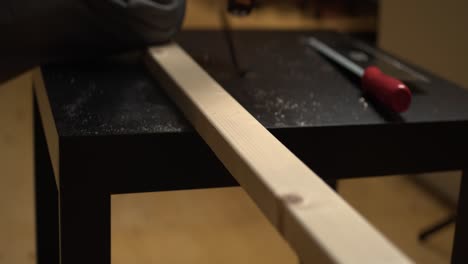 enfoque estrecho: el hombre mide y marca la madera de pino para cortar en una mesa pequeña