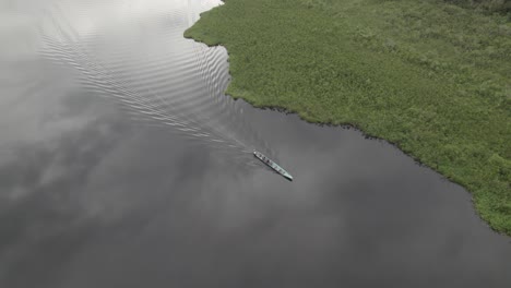 laguna negra con una pequeña lancha navegando en aguas tranquilas en colombia - toma aérea de drones