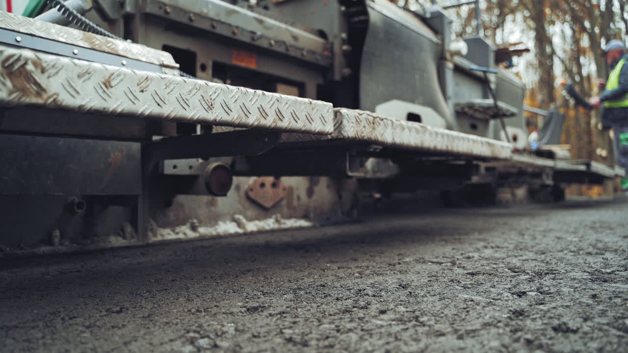 Close up asphalt laying machine. Asphalt paver. Tarmac road laying machine. Asphalt spreader. Road construction. Slow motion