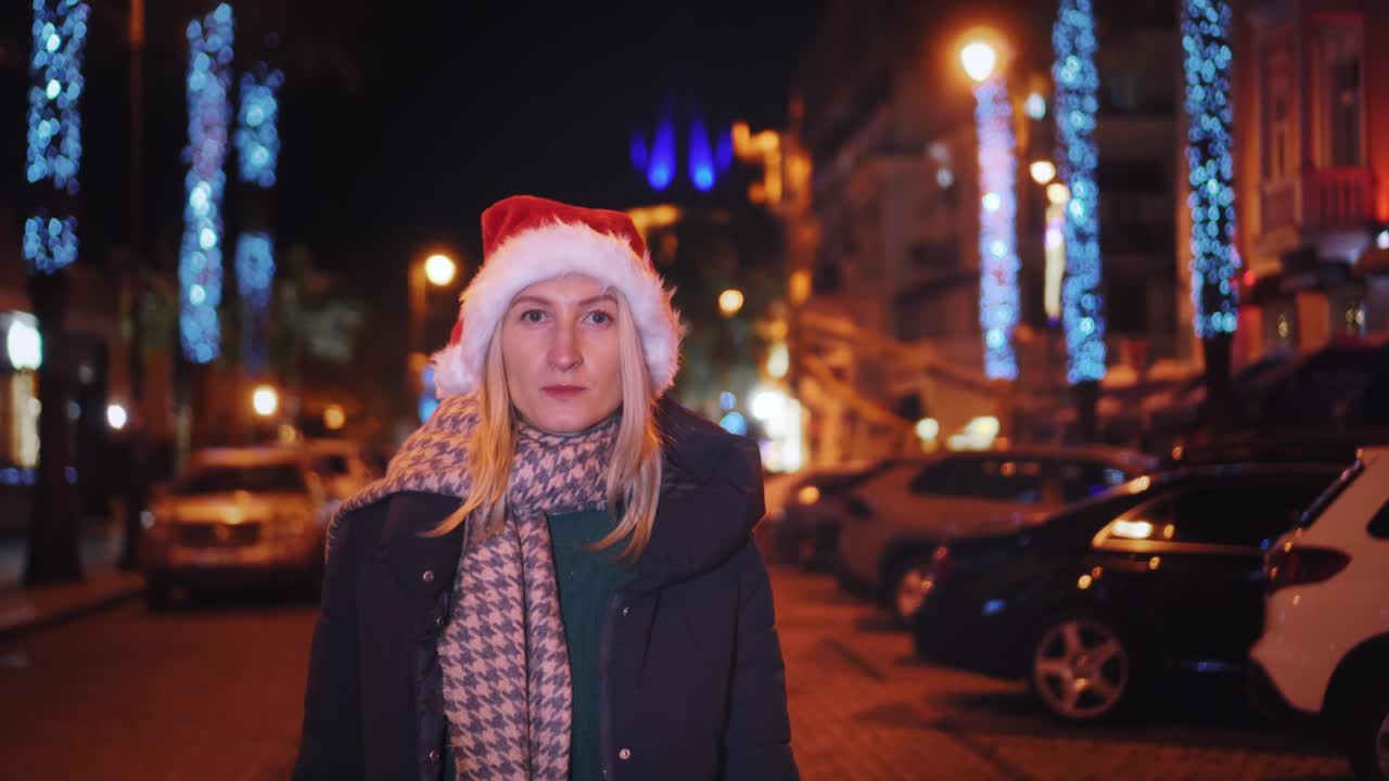 красивая женщина в шляпе санта-клауса ходит по ночам на рождество