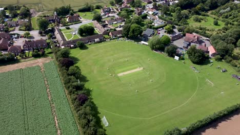 4k wide angle aerial video of a village cricket match in kent, england