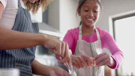 Feliz-Madre-Birracial-E-Hija-Haciendo-Mezcla-De-Pasteles,-Horneando-En-La-Cocina,-Cámara-Lenta