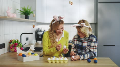mother and daughter painting easter eggs together
