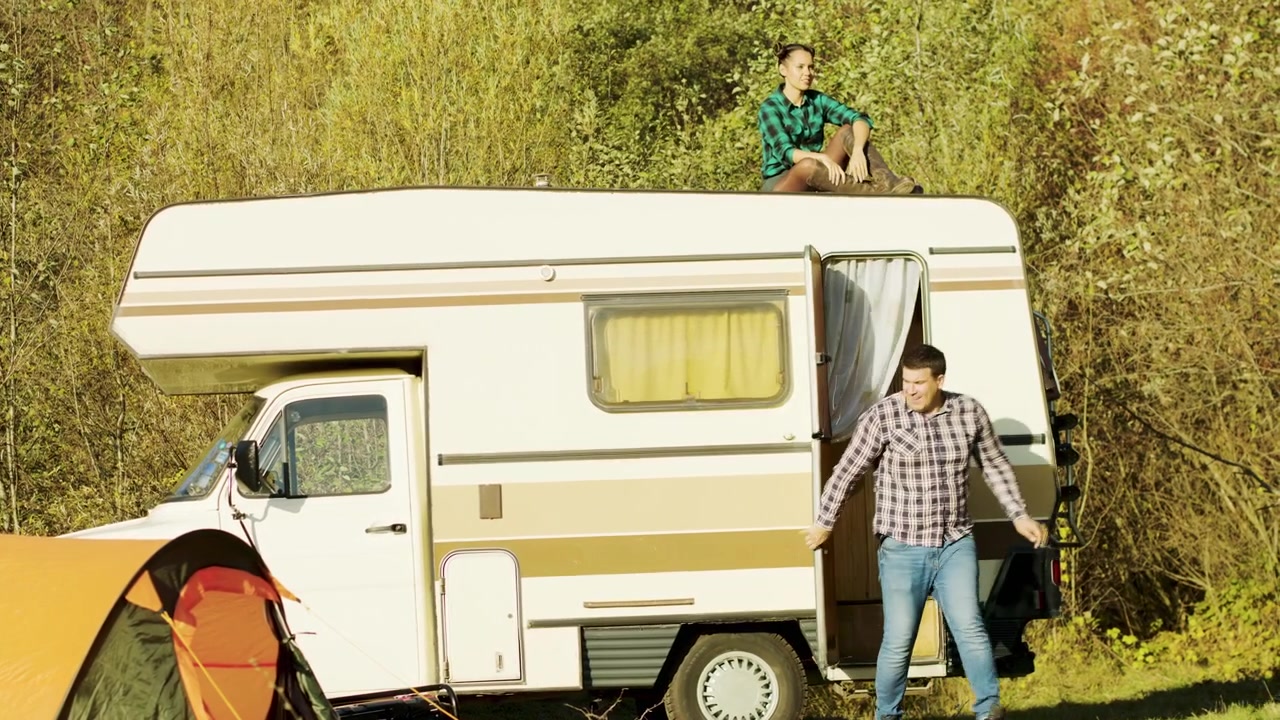 Mulher relaxa no teto de um trailer retrô nas montanhas