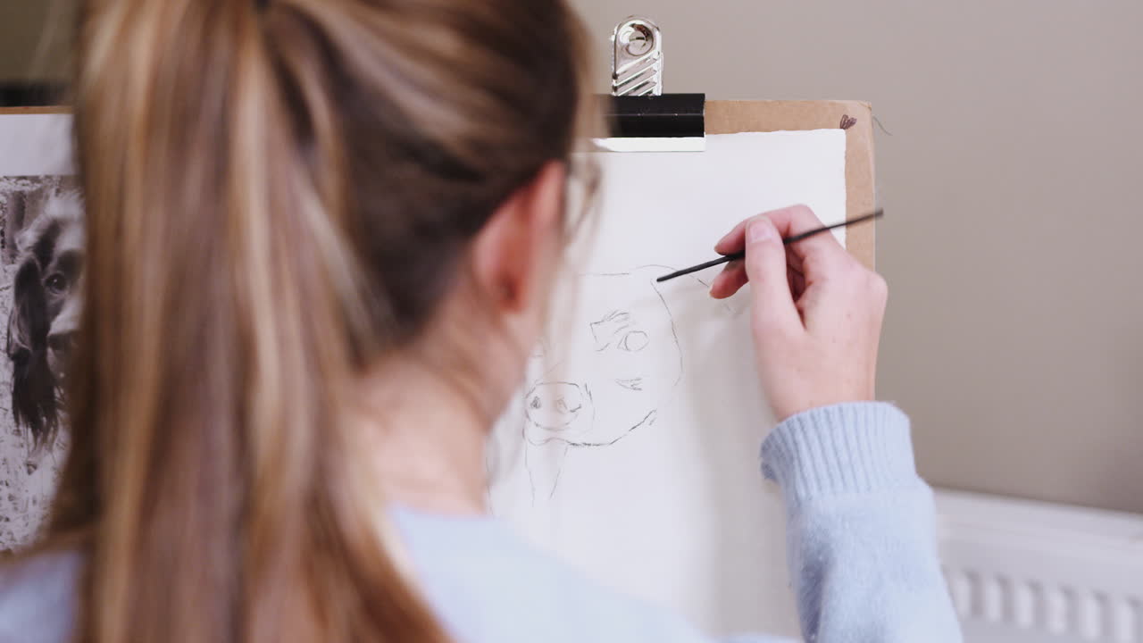 십대 여성 예술가 가 석탄 에 있는 사진 에서 개 의 그림 을 그리는 좌석 에 앉아 있다