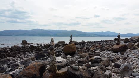 Ausgewogene-Spiritualität-Meditation-Kieselsteine-Aufgetürmt-Auf-Außerirdischen-Felsigen-Bergkette-Strand-Küste-Dolly-Links