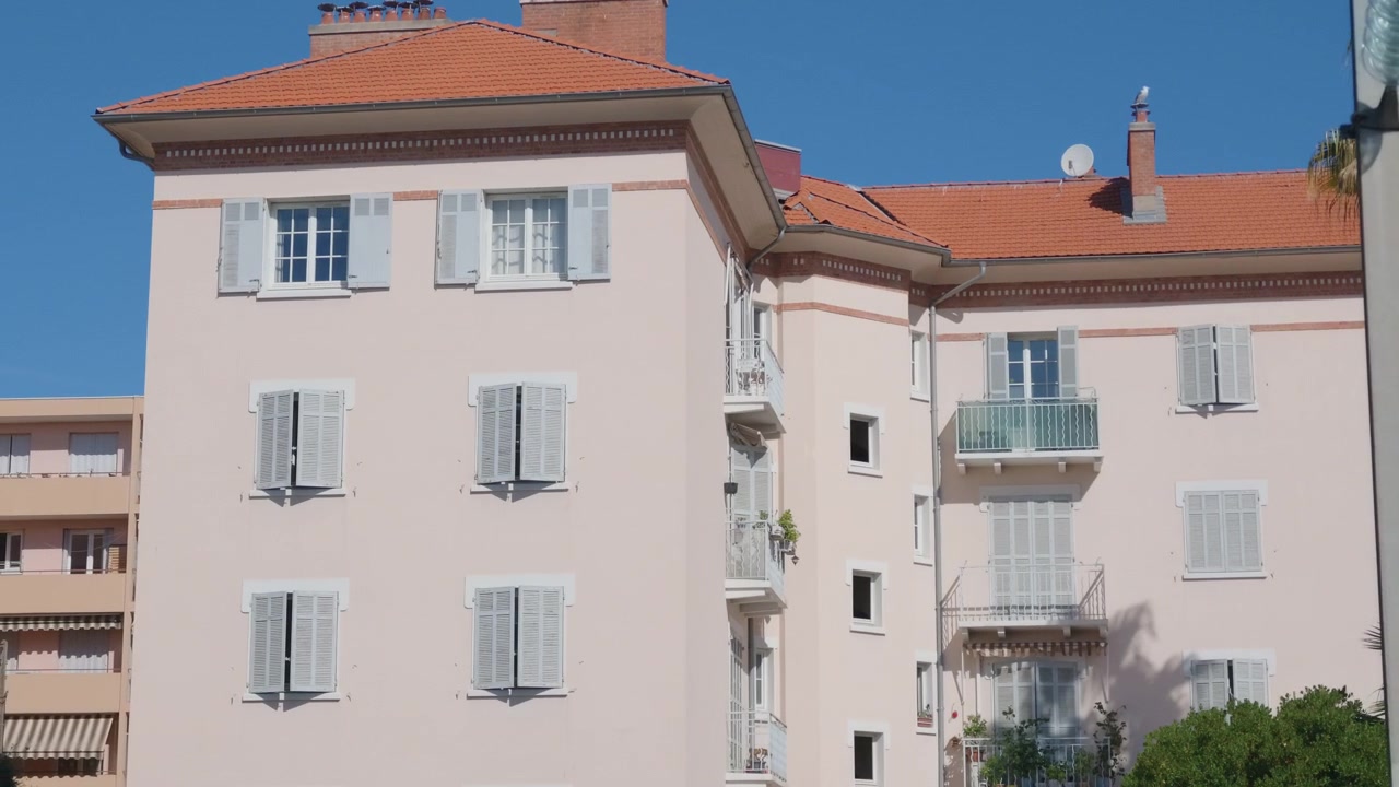 Ampia veduta di palazzi residenziali rosa e beige con finestre con persiane, Golfe-Juan, Francia