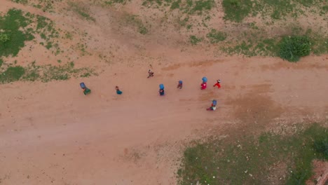 Drone-Toma-Una-Foto-De-Arriba-Hacia-Abajo-Del-Grupo-De-Personas-Que-Caminan-En-El-Camino-De-Arena-Cerca-Del-Fuerte-De-Umerkot-Y-Llevan-Sus-Cosas-En-La-Cabeza