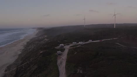 campistas de pie frente a praia da areira, portugal, durante la puesta de sol, aero