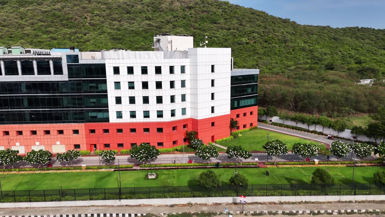 Business Park Design: Footage capturing a clean, modern institutional building with well-maintained grounds. The bold color accents and large windows symbolize corporate innovation and stable growth