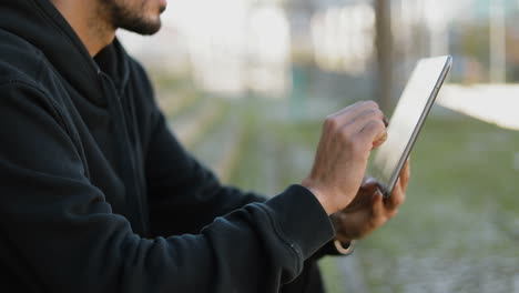 Medium-shot-of-young-handsome-mans-hands-in-black-hoodie-sitting-on-stairs-outside