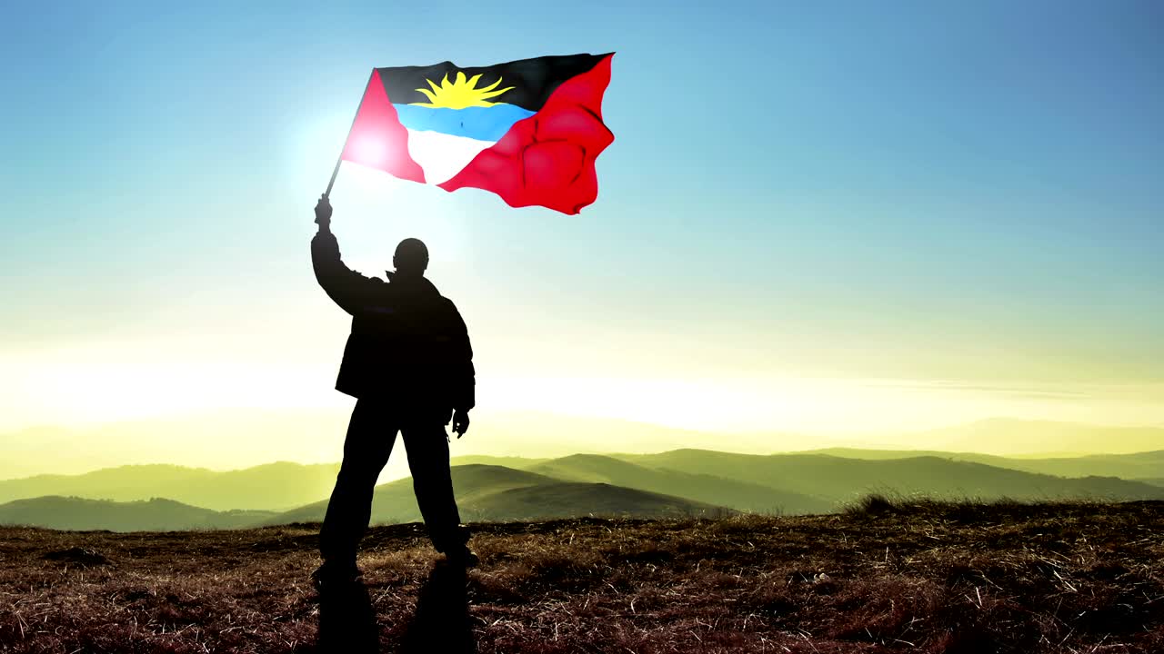 산꼭대기 위에서 안티구아와 바르부다 발을 흔들고 있는 성공적인 실루 남자 우승자.