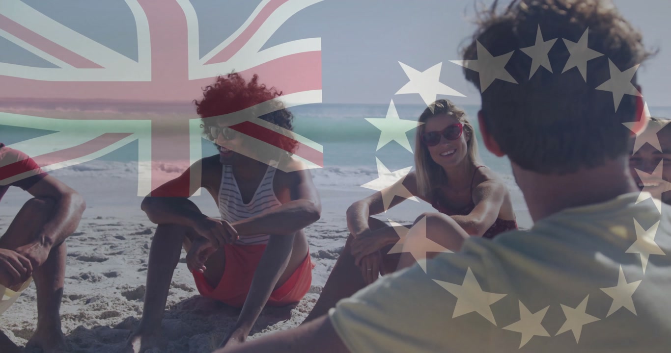 Group of friends arriving on sandy shoreline and settling in circle while sharing lively chat