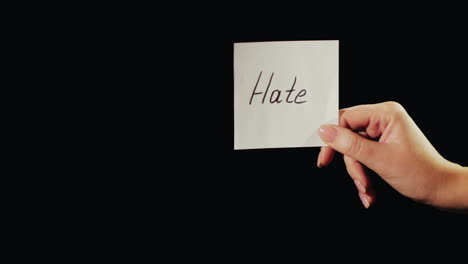 man burns a paper with the inscription hate