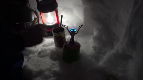 man lighting up a gas stove and placing a pot on it inside an igloo