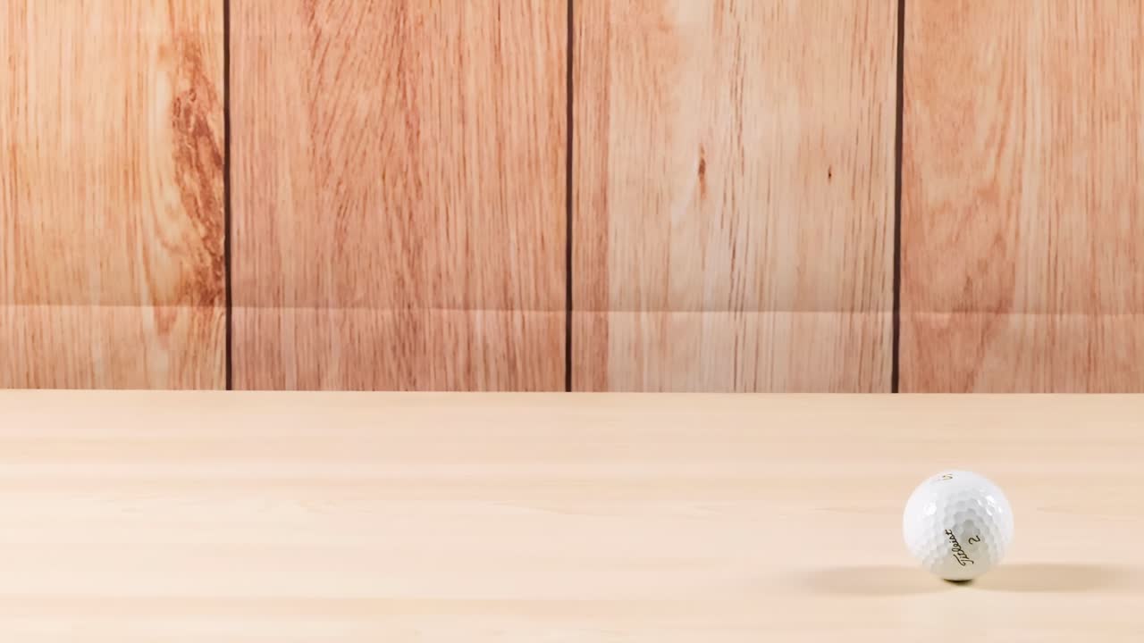 A golf ball bounces across a smooth wooden floor, showing dynamic motion and interaction with the surface.