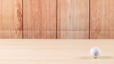a golf ball bounces across a smooth wooden floor, showing dynamic motion and interaction with the surface.
