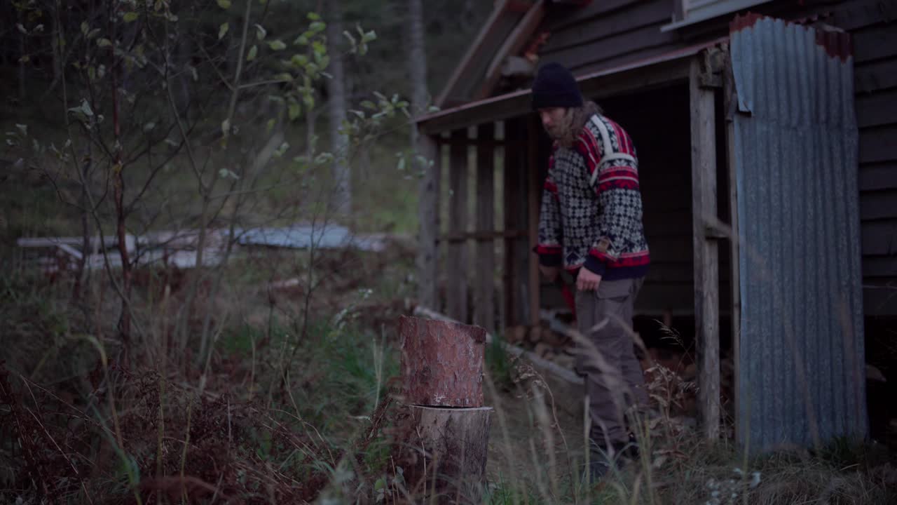 Mand i sweater hugger brænde med økse udendørs