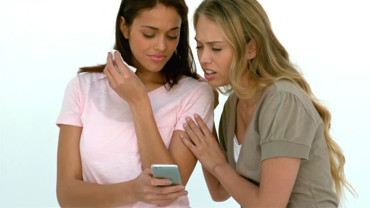 chica llorando mostrando a un amigo el teléfono inteligente