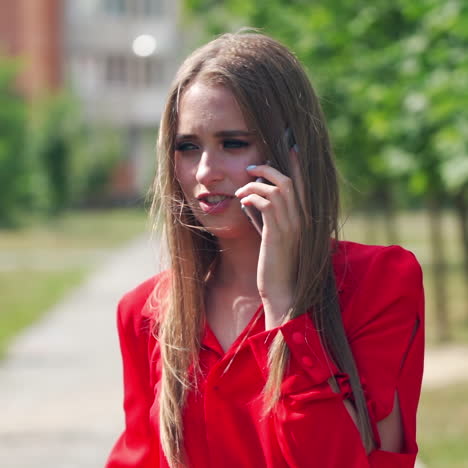 young woman talking on the phone. portrait of a beautiful lady with long hair holding a mobile phone on the blurred city background. slow motion.