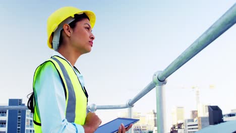 Woman-using-tablet-computer-and-looking-out-over-railing