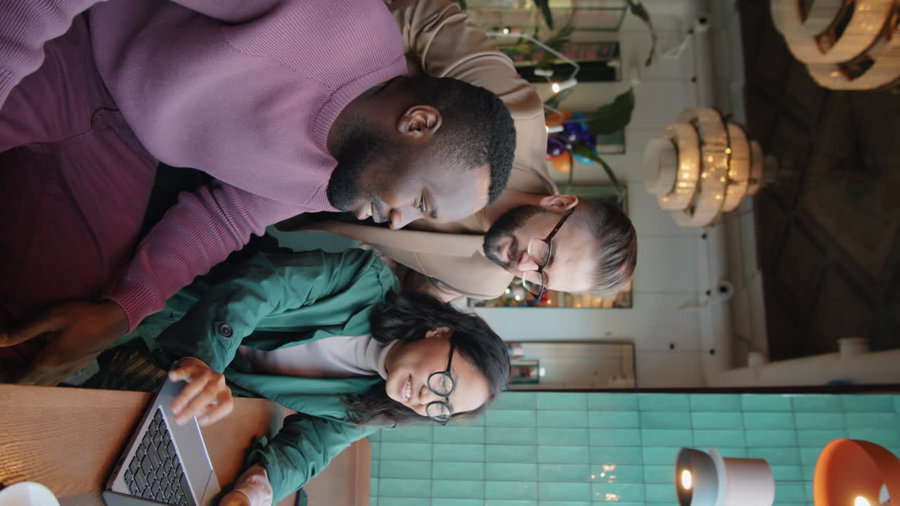 equipo de negocios multicultural trabajando en una computadora portátil en una cafetería