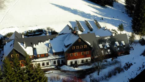 Aerial-drone-shot-over-a-big-wooden-cottage-along-Bielice-Mountain-slope-covered-with-thick-layers-of-snow-during-winter-season-in-Poland-at-daytime