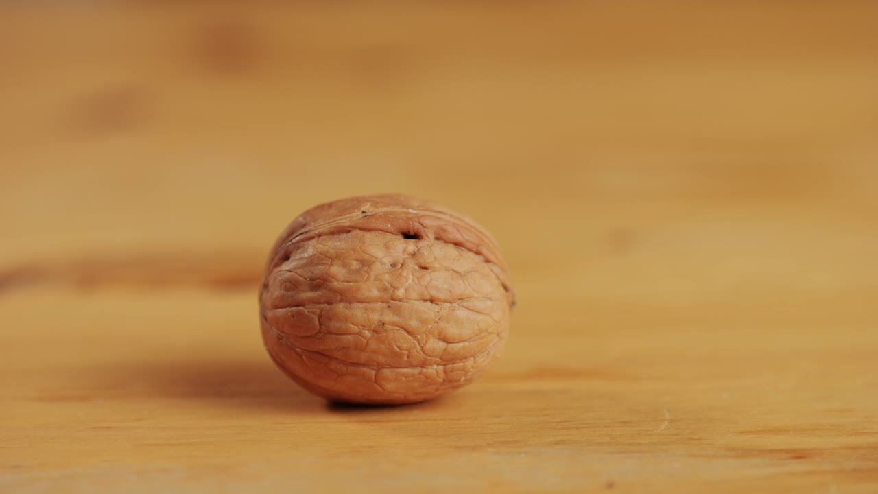 Craking walnut shell with hammer on wooden desk close-up. Healthy snacks. Product rich in minerals and vitamins.