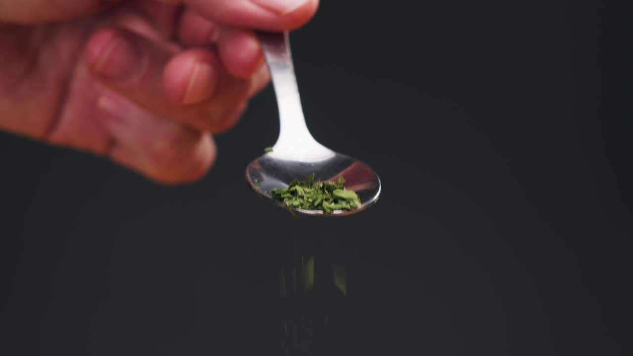 Dried green dill on spoon close-up macro. Spice for food. Man hand strewing dill on food . High quality 4k footage
