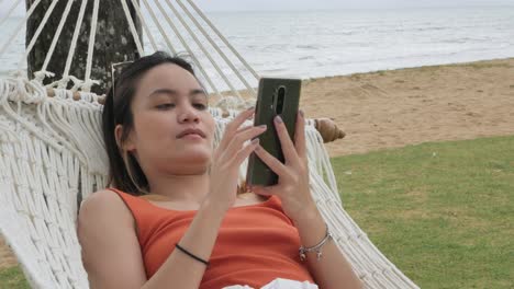 asian woman relaxing and on hammock near beach under coconut tree in vacation holiday time