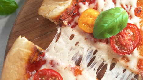 tearing slice of margherita pizza in slow motion - table top view of stretchy mozzarella cheese