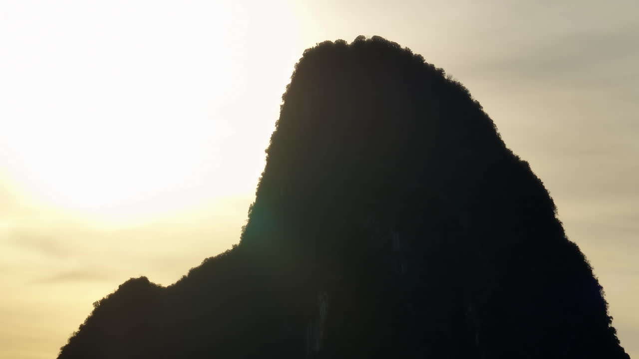 Telephoto aerial in front of backlit mountain peaks, sunset in Yangshuo, China