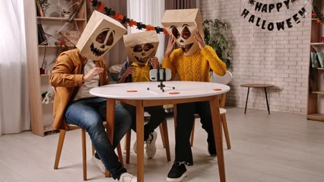 people in halloween paper bag masks recording a video at home